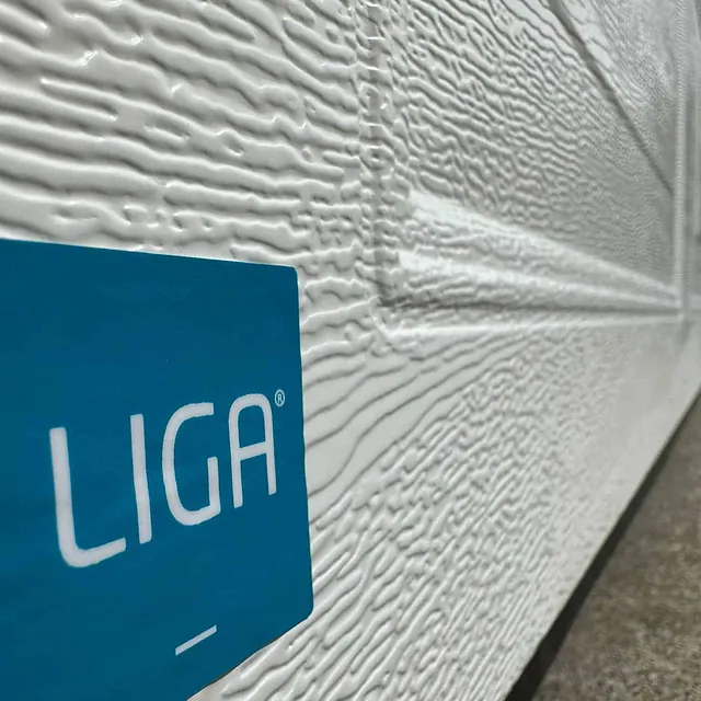 Nærbilde av hvit garasjeport med trestruktur og blått LIGA-merke nederst.